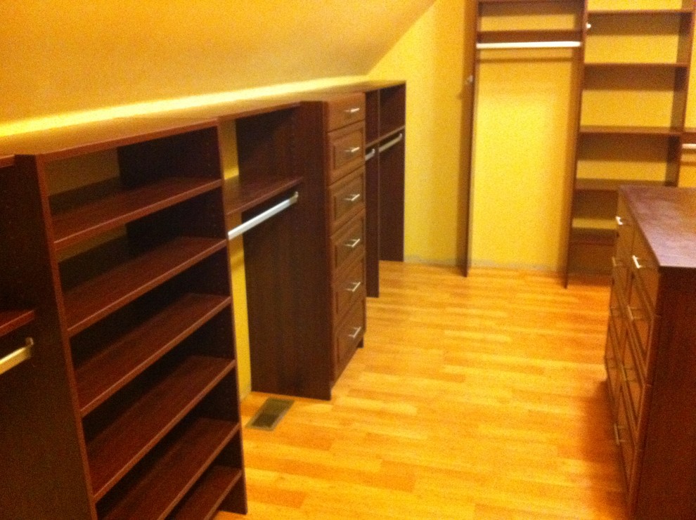 Foto de armario vestidor unisex clásico grande con armarios con paneles con relieve, puertas de armario de madera en tonos medios, suelo de madera clara y suelo beige