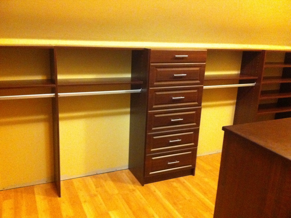 Photo of a large traditional gender neutral walk-in wardrobe in Other with raised-panel cabinets, dark wood cabinets, light hardwood flooring and beige floors.