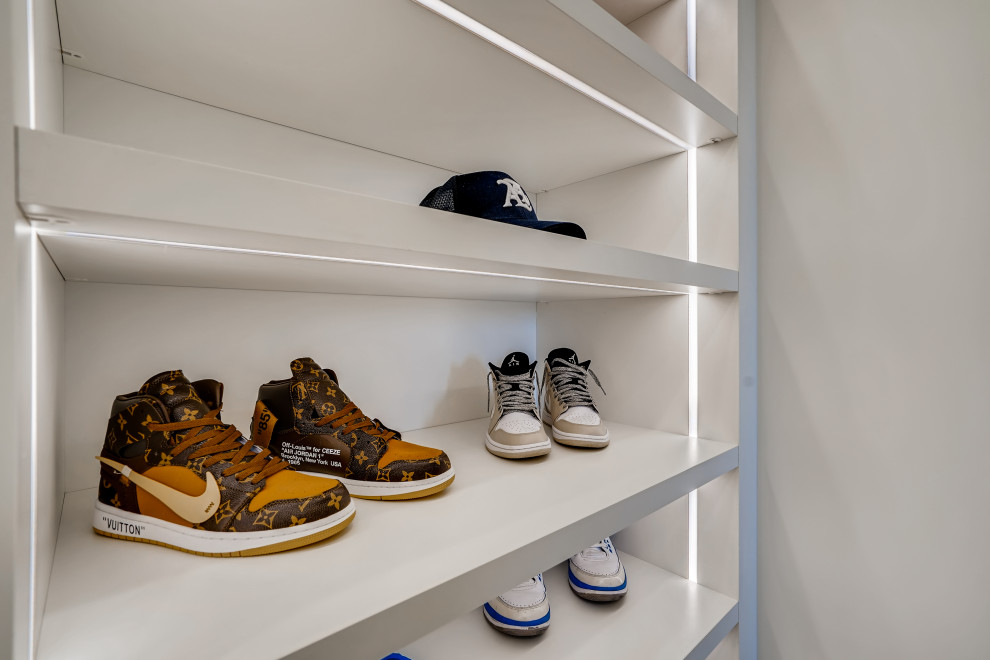 This is an example of a medium sized modern gender neutral walk-in wardrobe in Denver with flat-panel cabinets, white cabinets, light hardwood flooring and beige floors.