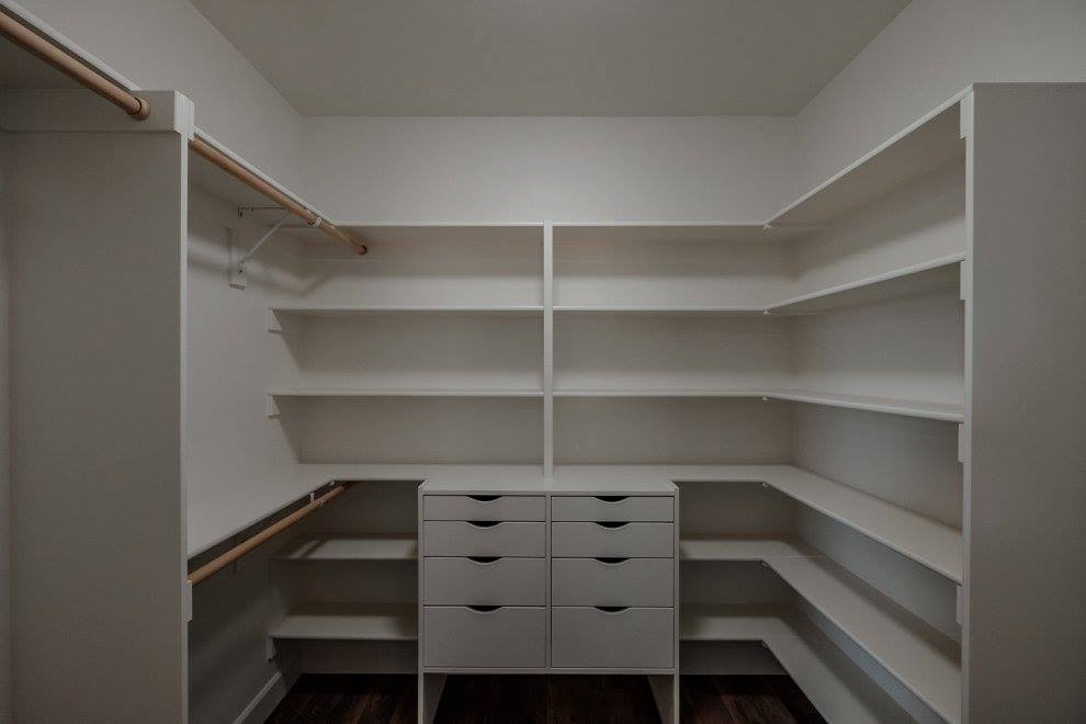 Inspiration for a gender neutral walk-in wardrobe in Portland with open cabinets, white cabinets and brown floors.