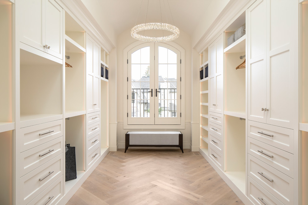 Стильный дизайн: гардеробная комната унисекс в стиле неоклассика (современная классика) с фасадами с утопленной филенкой, белыми фасадами и светлым паркетным полом - последний тренд
