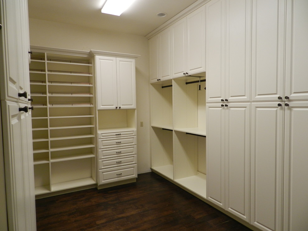 Modelo de armario vestidor unisex clásico grande con armarios con paneles con relieve, puertas de armario blancas, suelo de madera oscura y suelo marrón
