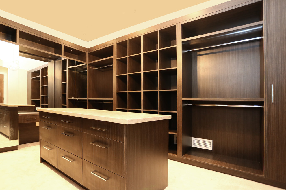 Expansive world-inspired walk-in wardrobe for women in Vancouver with open cabinets, dark wood cabinets and carpet.