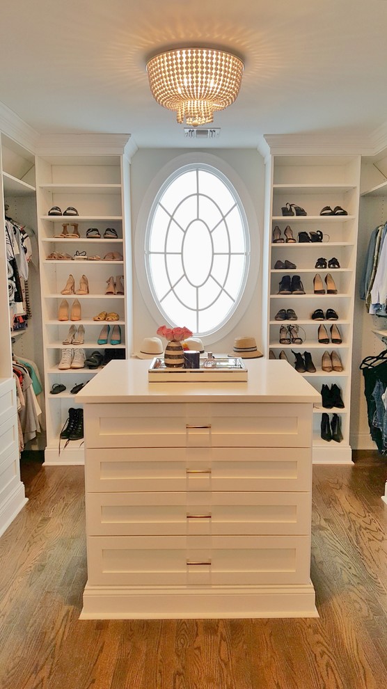 Modelo de armario vestidor de mujer minimalista de tamaño medio con puertas de armario blancas, suelo de madera oscura y suelo marrón