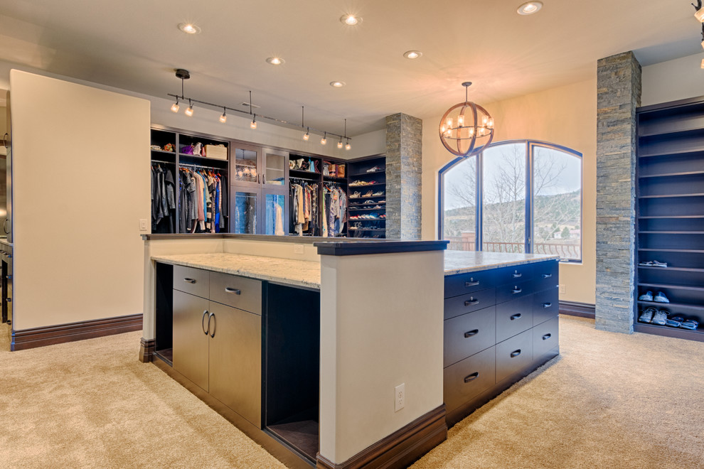 Inspiration for an expansive contemporary walk-in wardrobe in Denver with flat-panel cabinets, dark wood cabinets, carpet and beige floors.