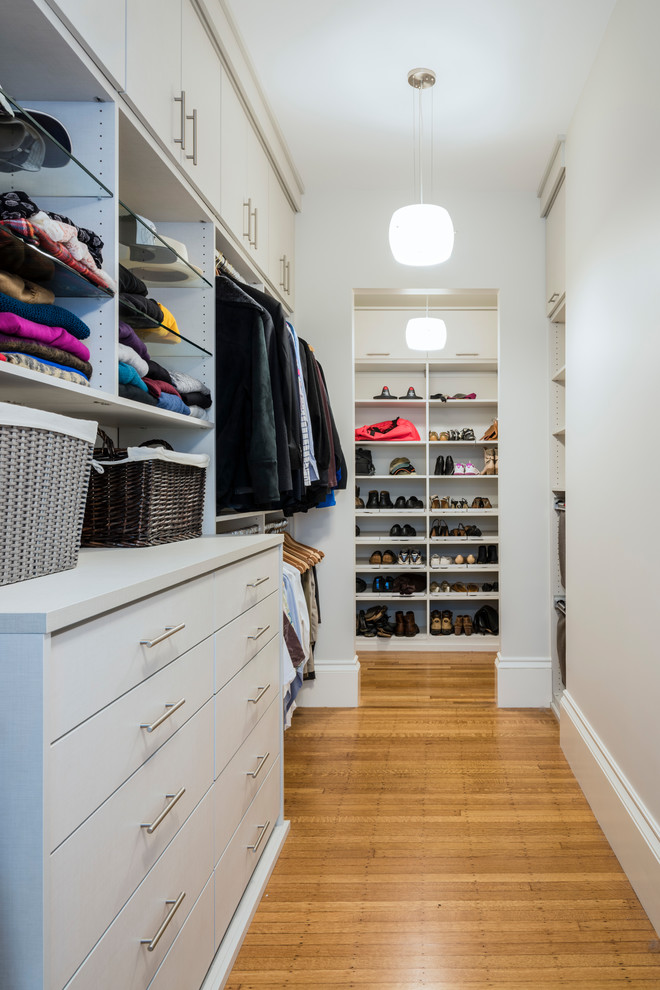 Example of a mid-sized transitional gender-neutral medium tone wood floor walk-in closet design in Boston with flat-panel cabinets and gray cabinets
