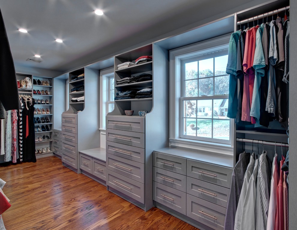 Imagen de armario vestidor unisex clásico grande con armarios estilo shaker, puertas de armario grises, suelo de madera en tonos medios y suelo marrón