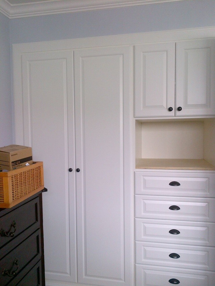 Imagen de armario unisex tradicional pequeño con armarios con paneles con relieve, puertas de armario blancas y suelo de madera clara