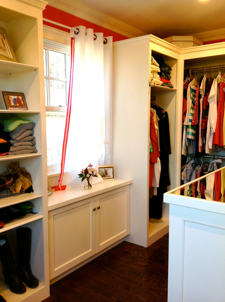 Example of a mid-sized classic women's dark wood floor and brown floor walk-in closet design in New York with raised-panel cabinets and white cabinets