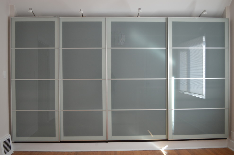 Inspiration for a medium sized contemporary standard wardrobe in Seattle with glass-front cabinets and medium hardwood flooring.