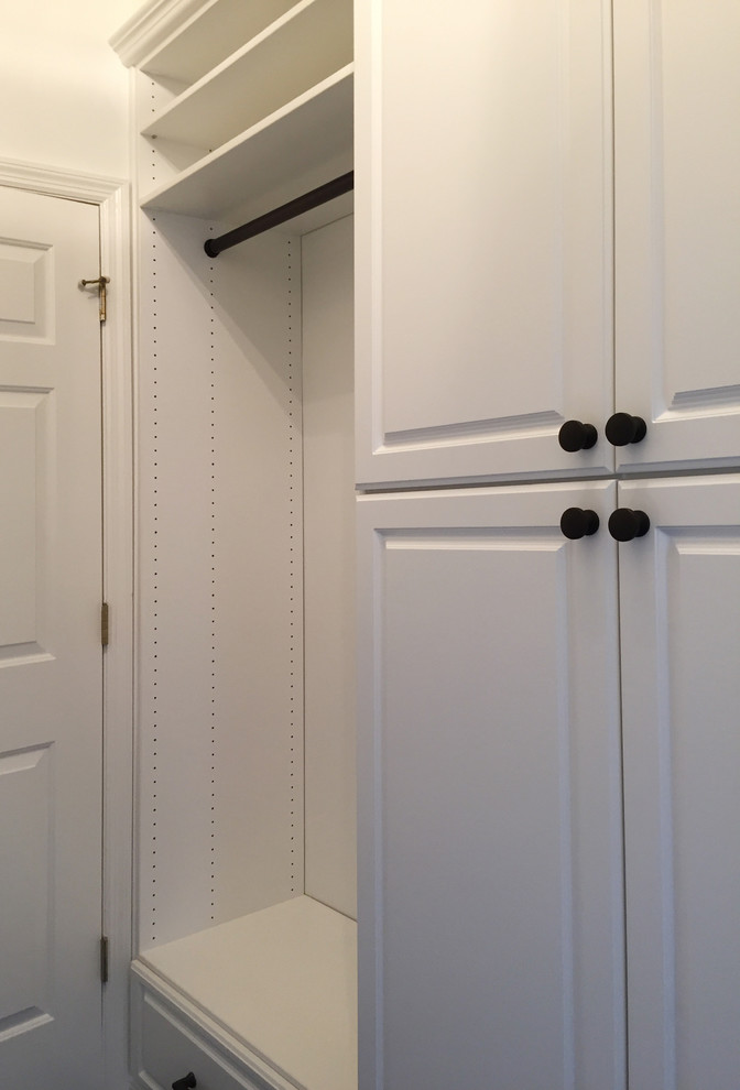 This is an example of a small traditional gender neutral walk-in wardrobe in Cincinnati with raised-panel cabinets, white cabinets and dark hardwood flooring.