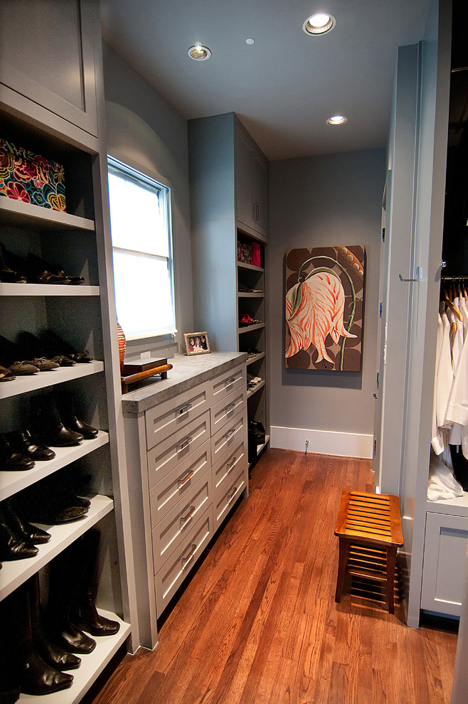 This is an example of a medium sized contemporary gender neutral walk-in wardrobe in Houston with shaker cabinets, grey cabinets and medium hardwood flooring.