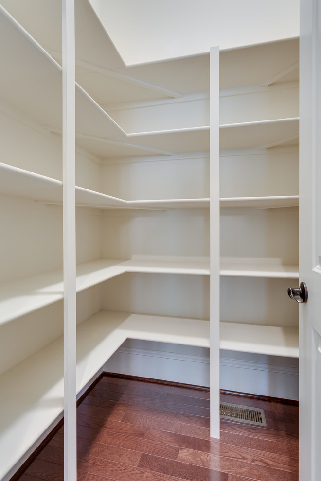 Photo of a medium sized traditional gender neutral walk-in wardrobe in DC Metro with open cabinets, white cabinets, dark hardwood flooring and brown floors.