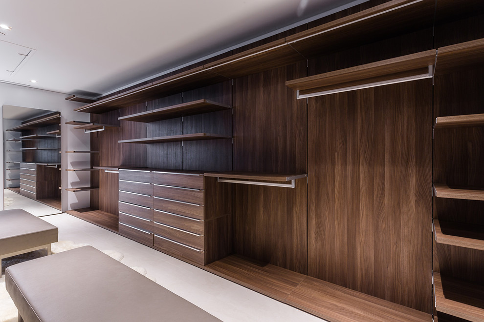 This is an example of a large contemporary gender neutral walk-in wardrobe in Los Angeles with flat-panel cabinets, light wood cabinets, ceramic flooring and beige floors.