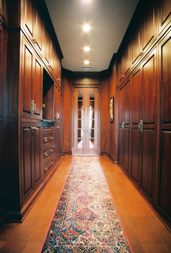 Foto di una grande cabina armadio unisex classica con ante con bugna sagomata, ante in legno bruno, pavimento in terracotta e pavimento marrone