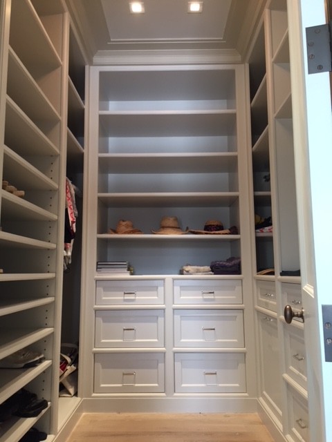 Inspiration for a medium sized traditional gender neutral dressing room in New York with recessed-panel cabinets, white cabinets, light hardwood flooring and beige floors.