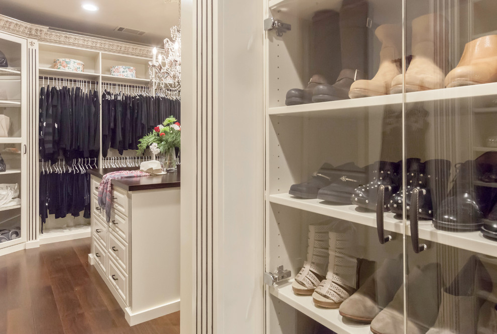 Ejemplo de armario vestidor de mujer clásico grande con armarios con paneles con relieve, puertas de armario beige y suelo de madera en tonos medios