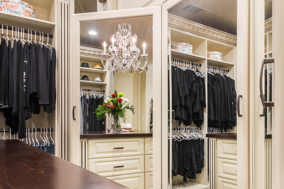Example of a large classic women's medium tone wood floor walk-in closet design in Los Angeles with raised-panel cabinets and beige cabinets
