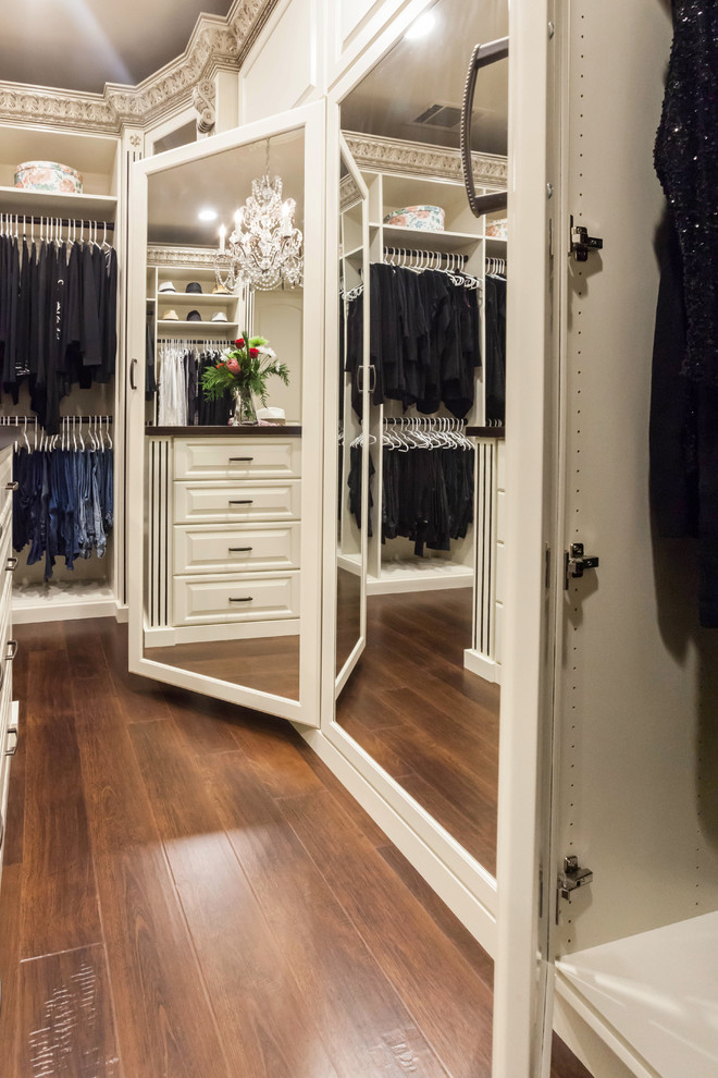 Ejemplo de armario vestidor de mujer tradicional grande con armarios con paneles con relieve, puertas de armario beige y suelo de madera en tonos medios