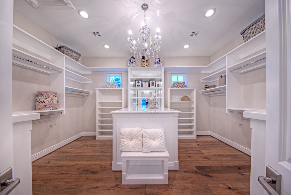 Inspiration for a large classic gender neutral walk-in wardrobe in Phoenix with open cabinets, white cabinets and medium hardwood flooring.