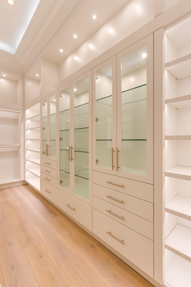 Inspiration for a large transitional women's medium tone wood floor and brown floor walk-in closet remodel in Other with flat-panel cabinets and white cabinets