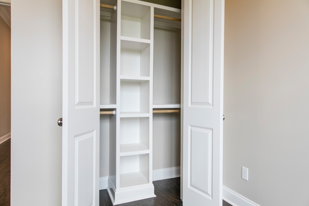На фото: шкаф в нише среднего размера, унисекс в стиле неоклассика (современная классика) с белыми фасадами, полом из ламината и коричневым полом с