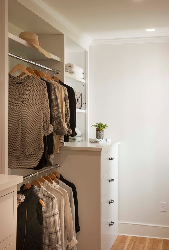 Imagen de armario vestidor unisex tradicional renovado pequeño con puertas de armario blancas y suelo de madera en tonos medios