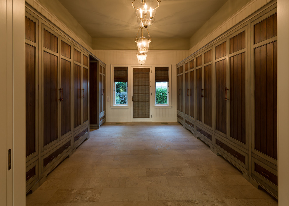 На фото: огромная гардеробная комната унисекс в классическом стиле с полом из известняка и бежевым полом с