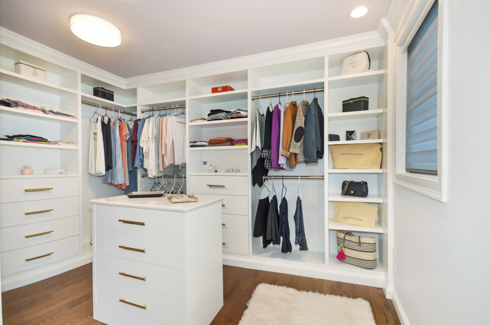 Photo of a large classic walk-in wardrobe for women in Boston with flat-panel cabinets, white cabinets, medium hardwood flooring and brown floors.