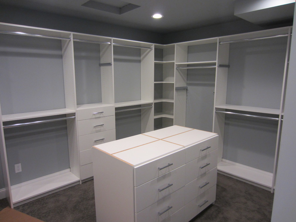 Inspiration for a large traditional gender neutral walk-in wardrobe in Other with flat-panel cabinets, white cabinets and carpet.