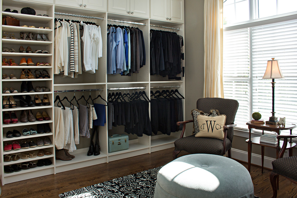 Imagen de armario vestidor unisex actual grande con armarios con paneles con relieve, puertas de armario blancas, suelo de madera oscura y suelo marrón