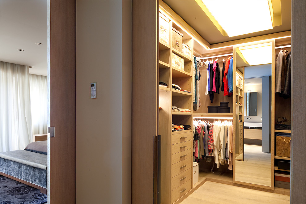 Cette image montre un dressing design en bois clair de taille moyenne et neutre avec un placard sans porte et parquet clair.