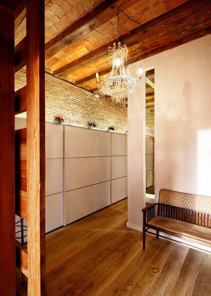 Cette photo montre un dressing tendance avec des portes de placard blanches et un sol en bois brun.
