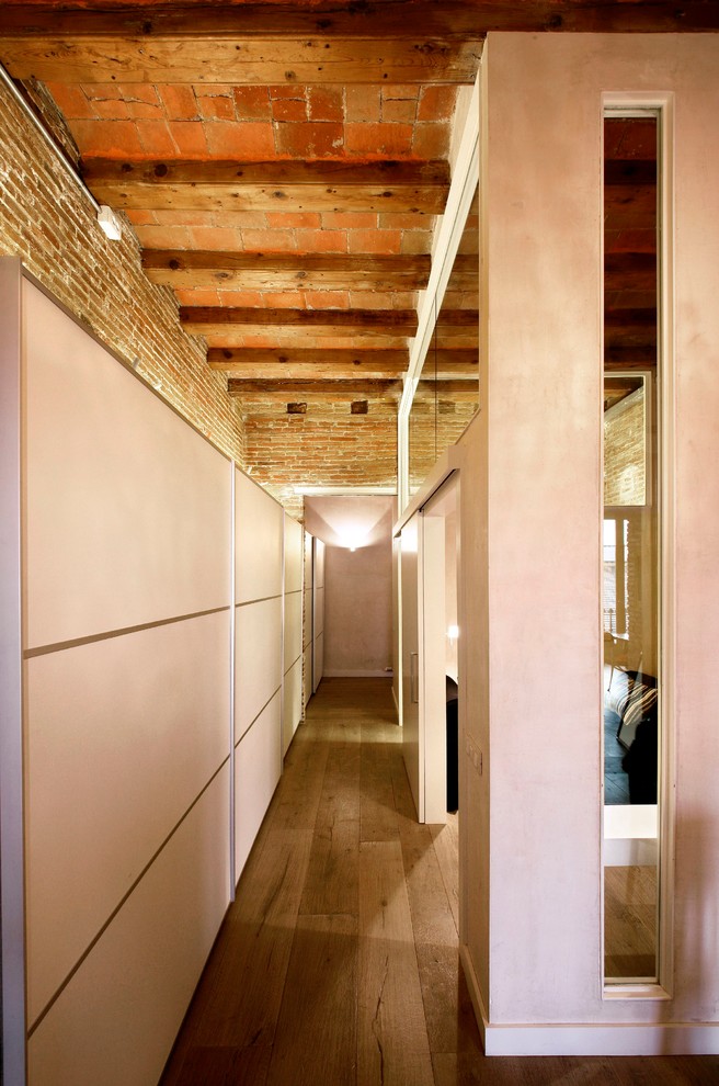 Aménagement d'un dressing contemporain avec des portes de placard blanches et un sol en bois brun.