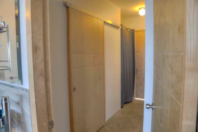 Modern inredning av ett walk-in-closet för könsneutrala, med luckor med upphöjd panel, skåp i ljust trä och betonggolv