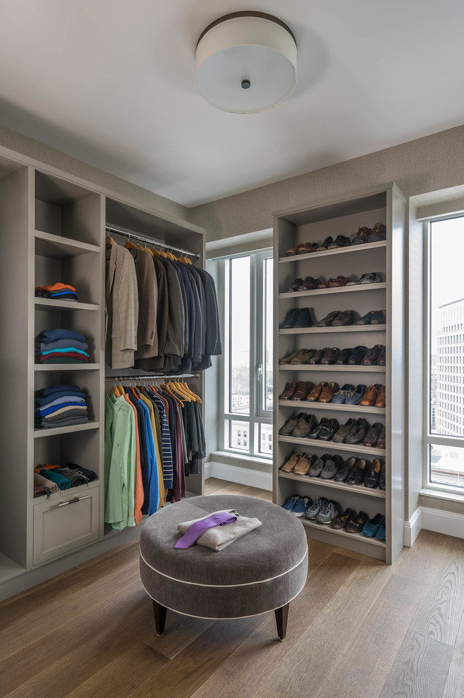 This is an example of a classic dressing room for men in Boston with open cabinets, grey cabinets, medium hardwood flooring and beige floors.