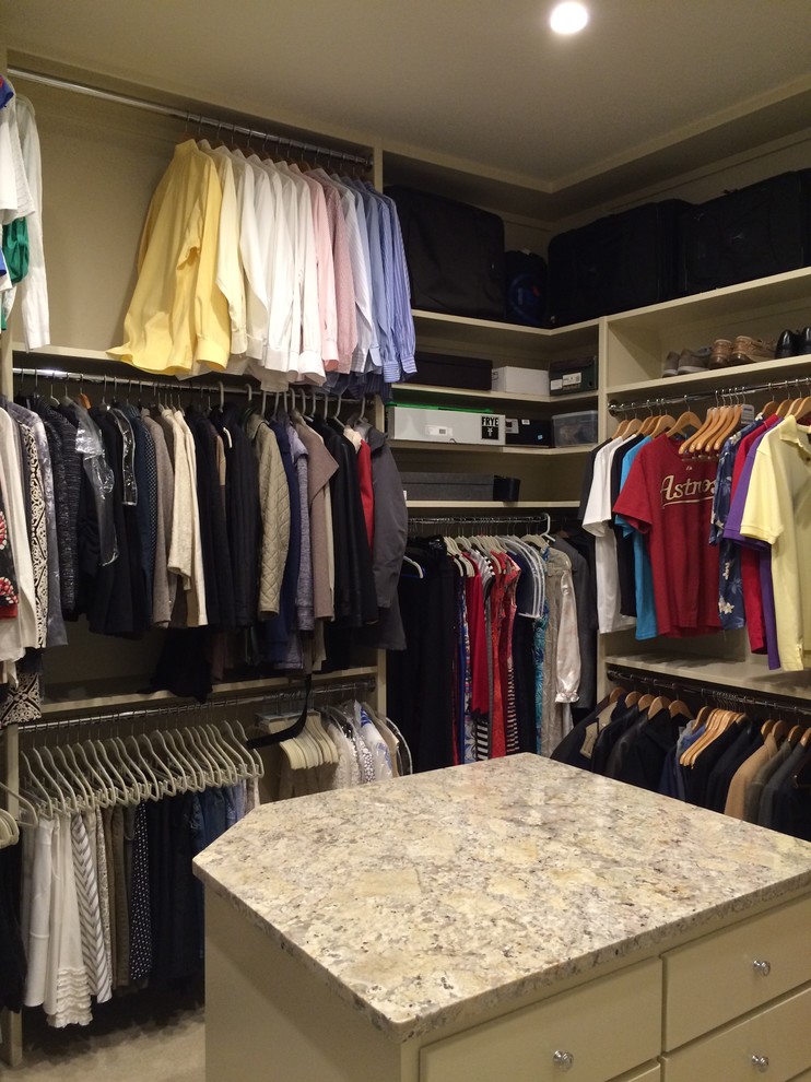 Large traditional gender neutral walk-in wardrobe in Houston with flat-panel cabinets, beige cabinets and carpet.