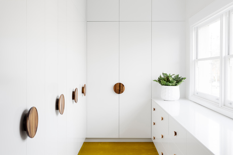 Стильный дизайн: гардеробная комната среднего размера, унисекс в современном стиле с плоскими фасадами, белыми фасадами, ковровым покрытием и желтым полом - последний тренд