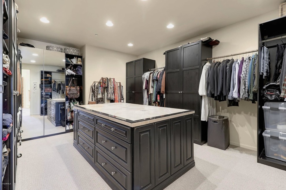 Пример оригинального дизайна: большая гардеробная комната унисекс с черными фасадами, ковровым покрытием и белым полом