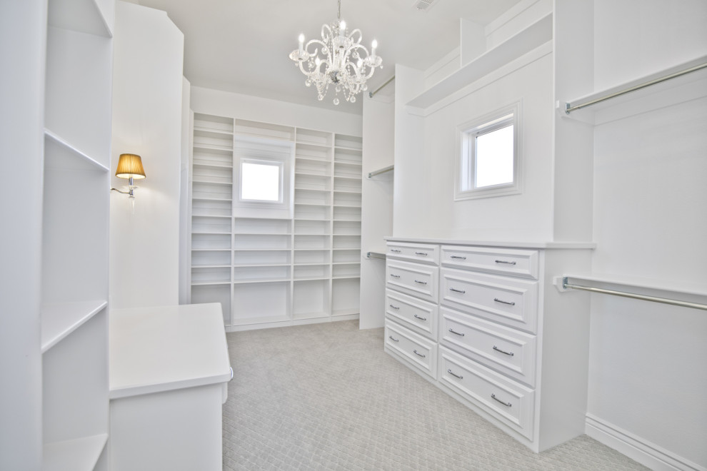 Large traditional walk-in wardrobe in Other with beaded cabinets, white cabinets, carpet and grey floors.