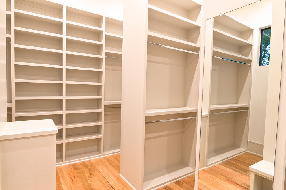 Example of a mid-sized minimalist gender-neutral medium tone wood floor and brown floor dressing room design with open cabinets and white cabinets