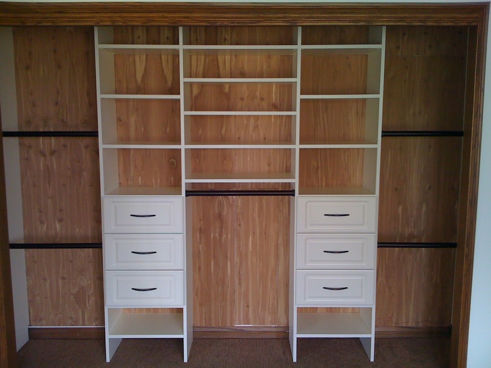 Example of a large classic gender-neutral medium tone wood floor reach-in closet design in Other with raised-panel cabinets and white cabinets