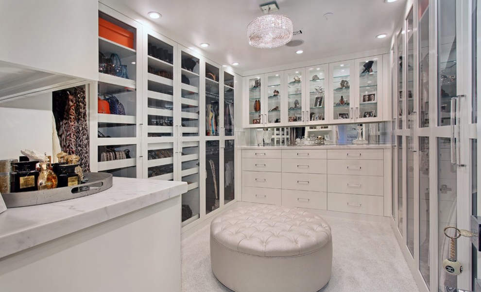 Medium sized nautical walk-in wardrobe for women in New York with glass-front cabinets, carpet and white cabinets.
