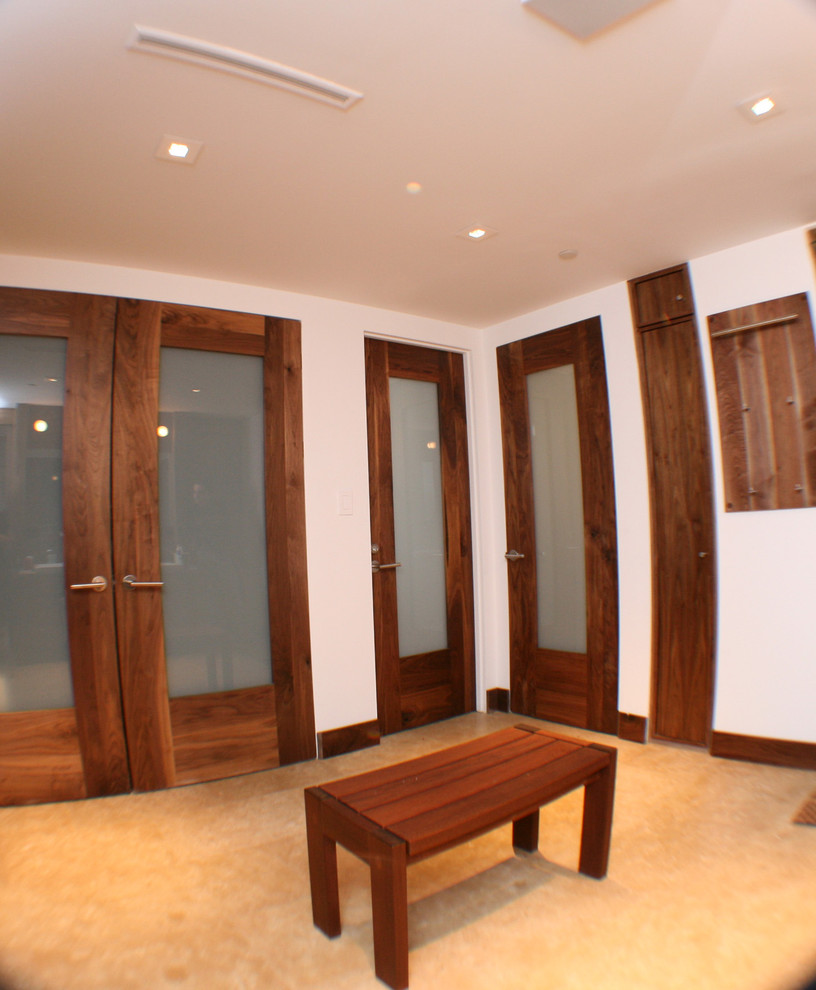 Imagen de armario y vestidor unisex moderno de tamaño medio con armarios con paneles lisos, puertas de armario de madera oscura y suelo de baldosas de cerámica