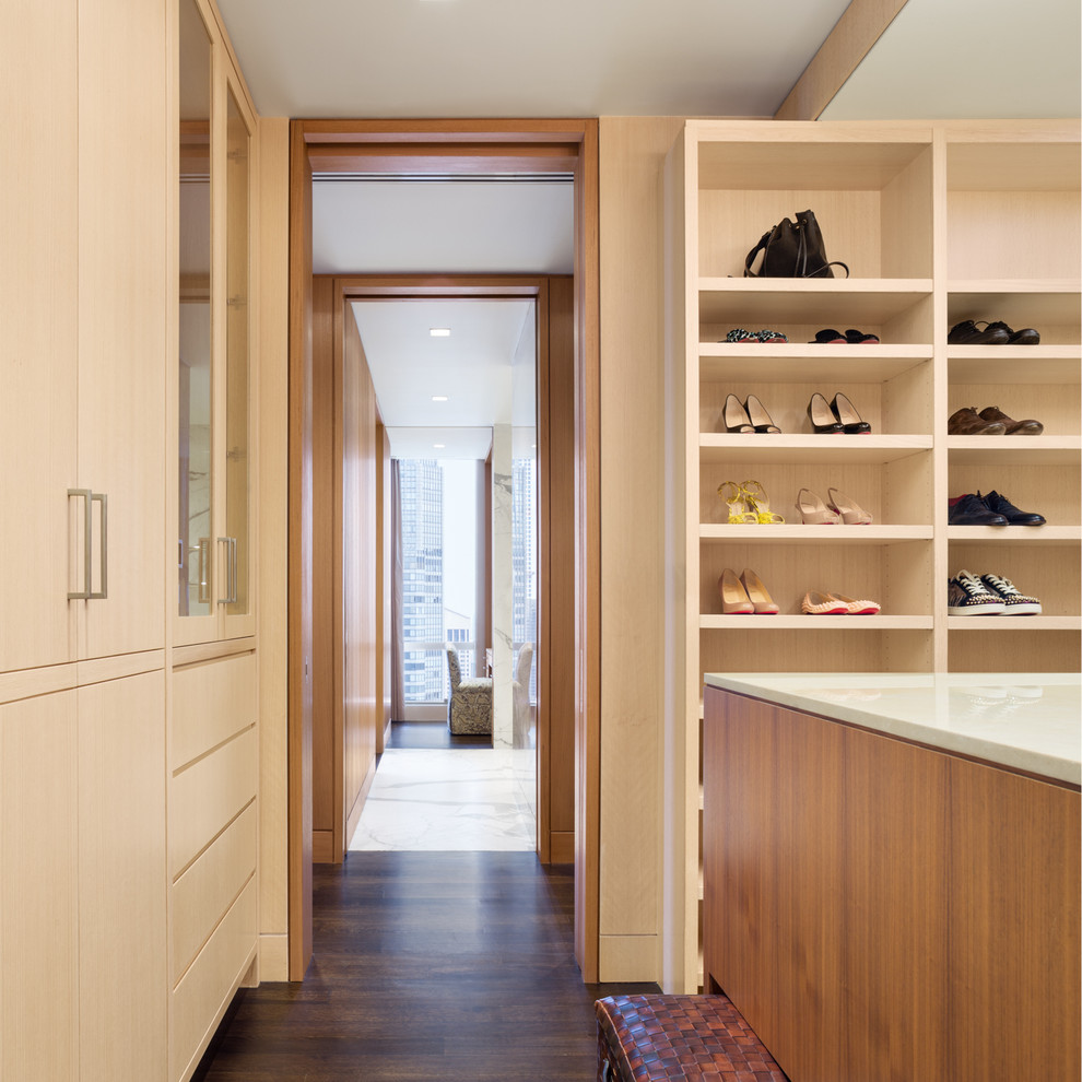 На фото: большая гардеробная комната унисекс в современном стиле с плоскими фасадами, светлыми деревянными фасадами, темным паркетным полом и коричневым полом