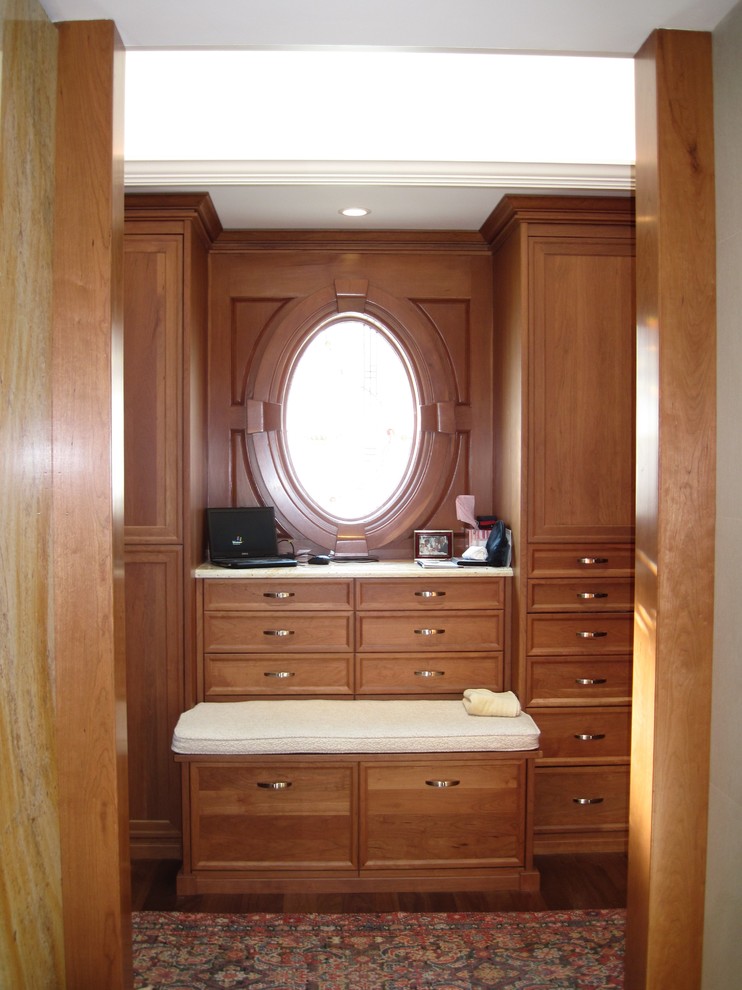 Imagen de armario y vestidor bohemio con puertas de armario de madera oscura y suelo de madera en tonos medios