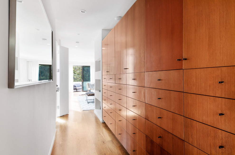 Réalisation d'un dressing minimaliste en bois brun de taille moyenne et neutre avec un placard à porte plane, un sol en bois brun et un sol beige.