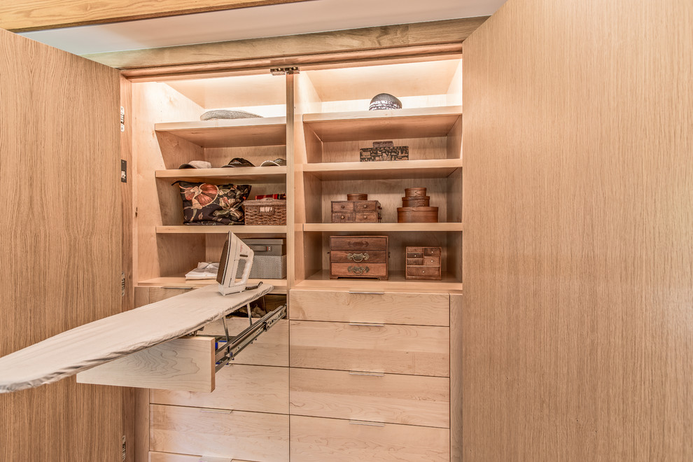 Diseño de armario unisex retro de tamaño medio con armarios con paneles lisos, puertas de armario de madera clara, suelo de madera clara y suelo beige