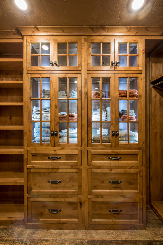 Ejemplo de armario vestidor unisex rural de tamaño medio con armarios con paneles empotrados, puertas de armario de madera oscura y suelo de madera oscura