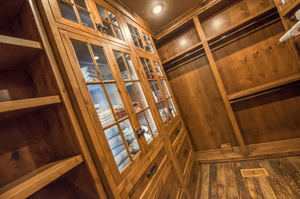 Inspiration for a mid-sized rustic gender-neutral dark wood floor walk-in closet remodel in Other with recessed-panel cabinets and medium tone wood cabinets